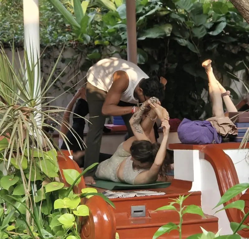 Teacher guiding a deep backbend in the garden pavilion