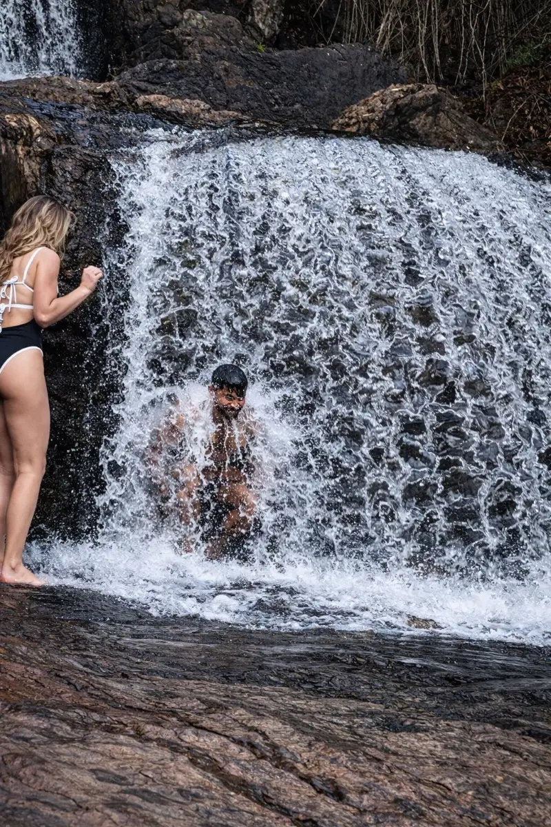 Students cooling off beneath a waterfall on a retreat day trip